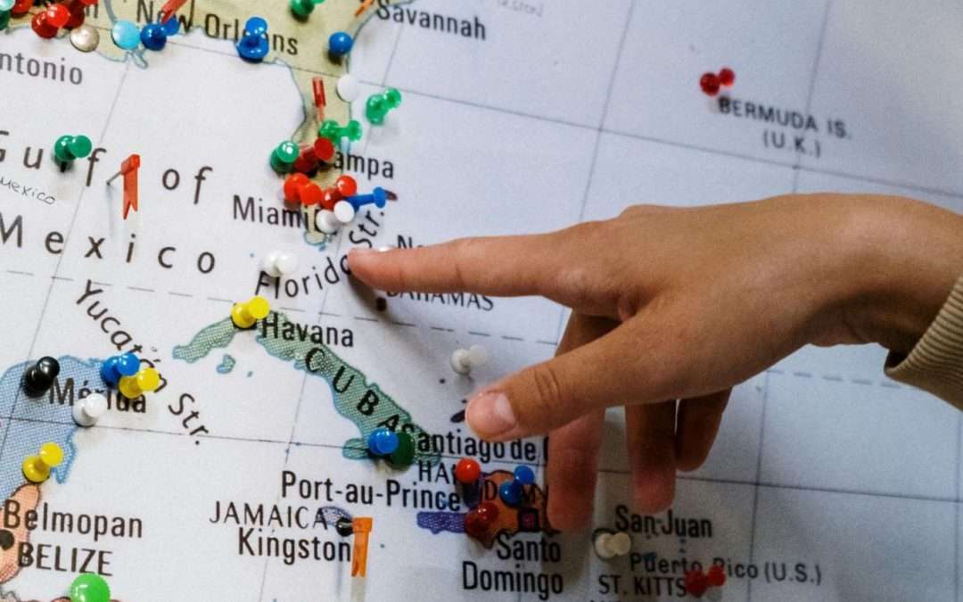 hand pointing to caribbean on world map